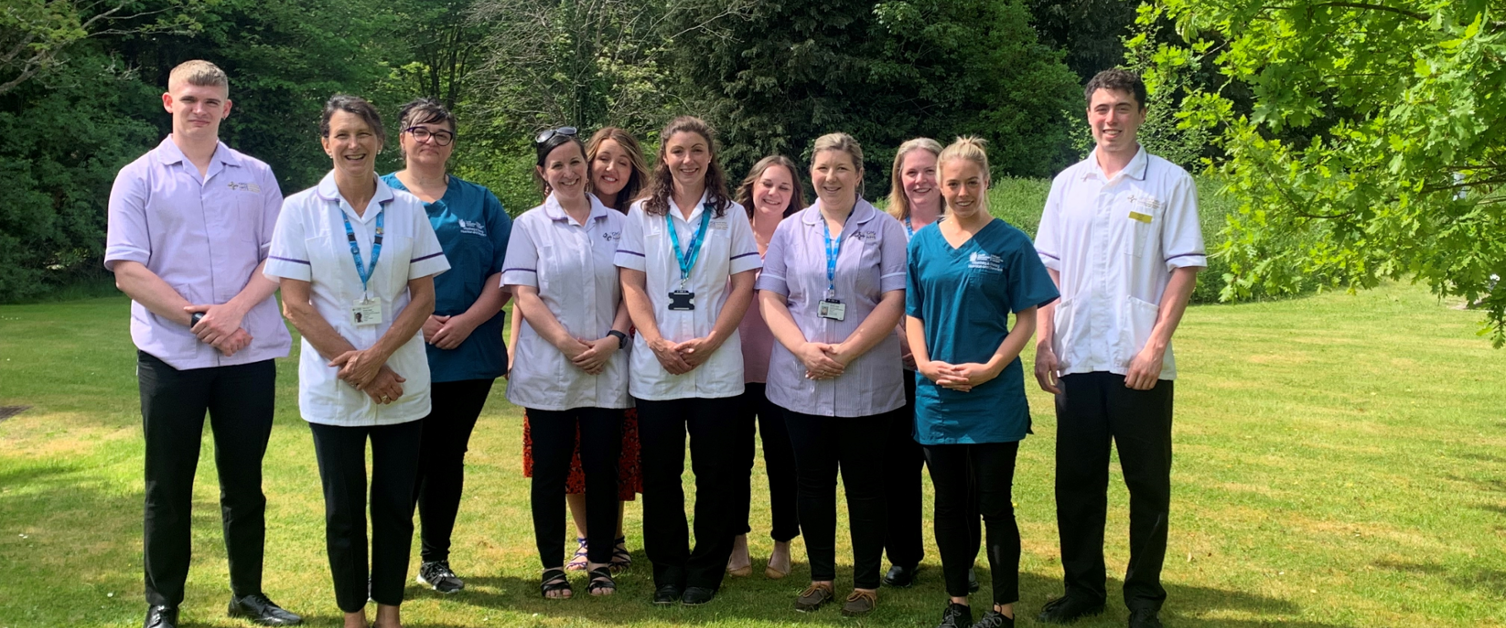 The Powys Teaching Health Board (PTHB) Dietetics Team members, stood outside for a group photo, with trees behind