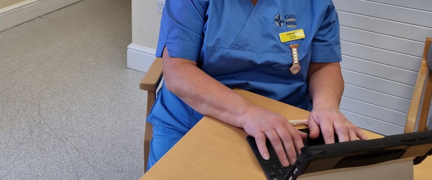 Linda Hamer, first nurse to use a digital nursing care record in Llandrindod Wells sits at table with tablet