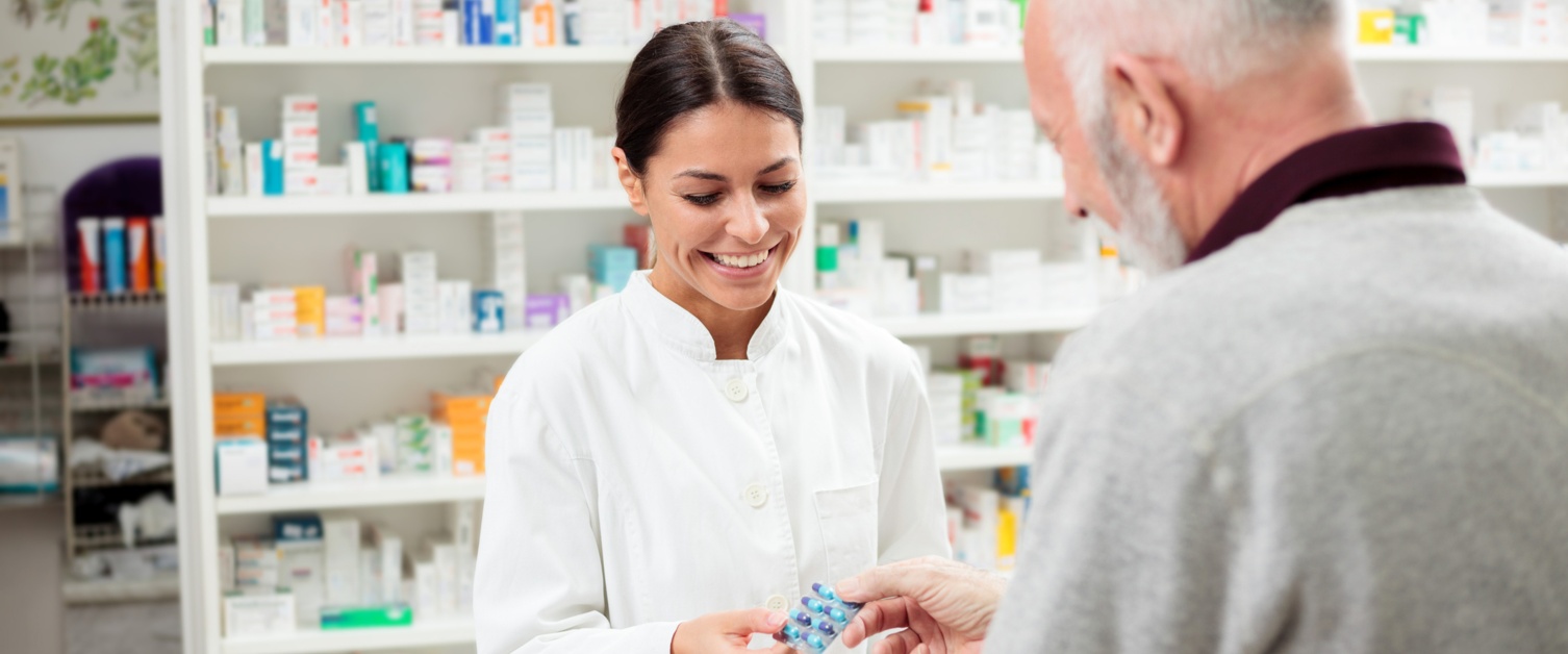 Medicine, pharmaceutics, health care and people concept - Happy female pharmacist giving medications to senior male customer
