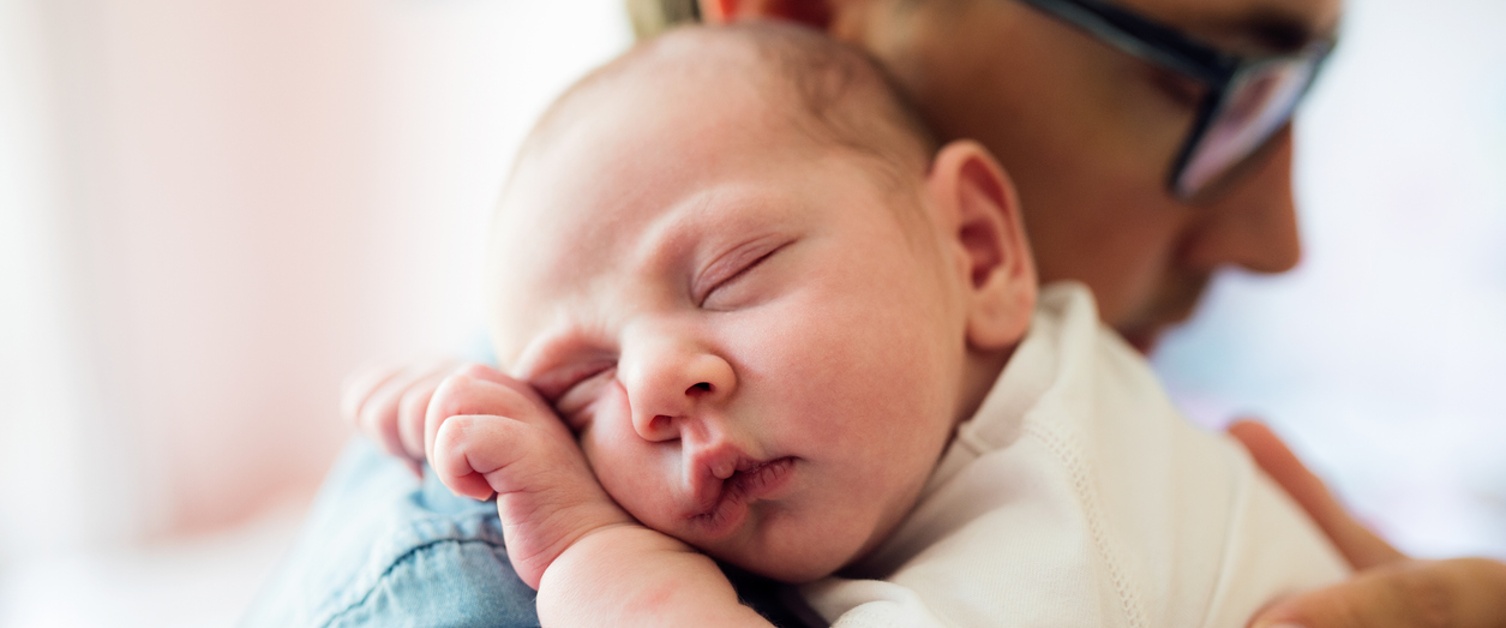 Close up of young father holding his newborn baby son in his arms