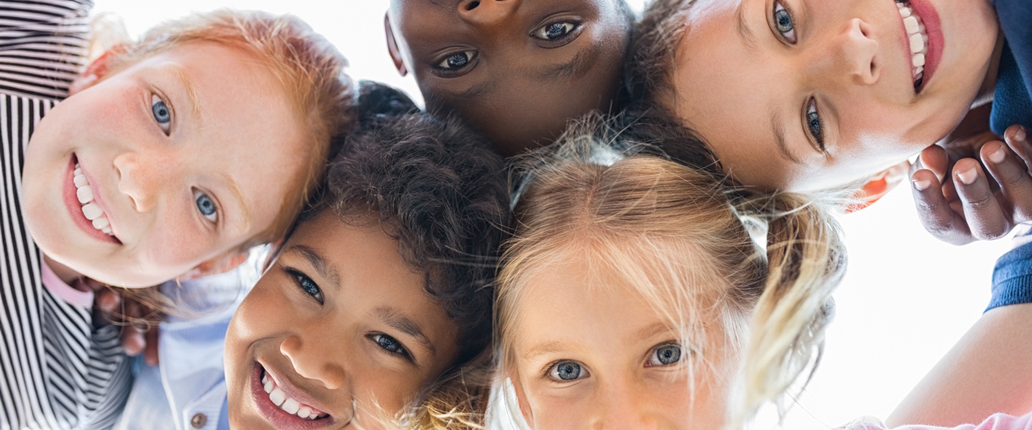 Team of smiling kids embracing together in a circle.