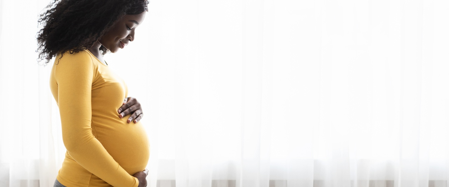 pregnant black woman hugging her tummy, enjoying her pregnancy