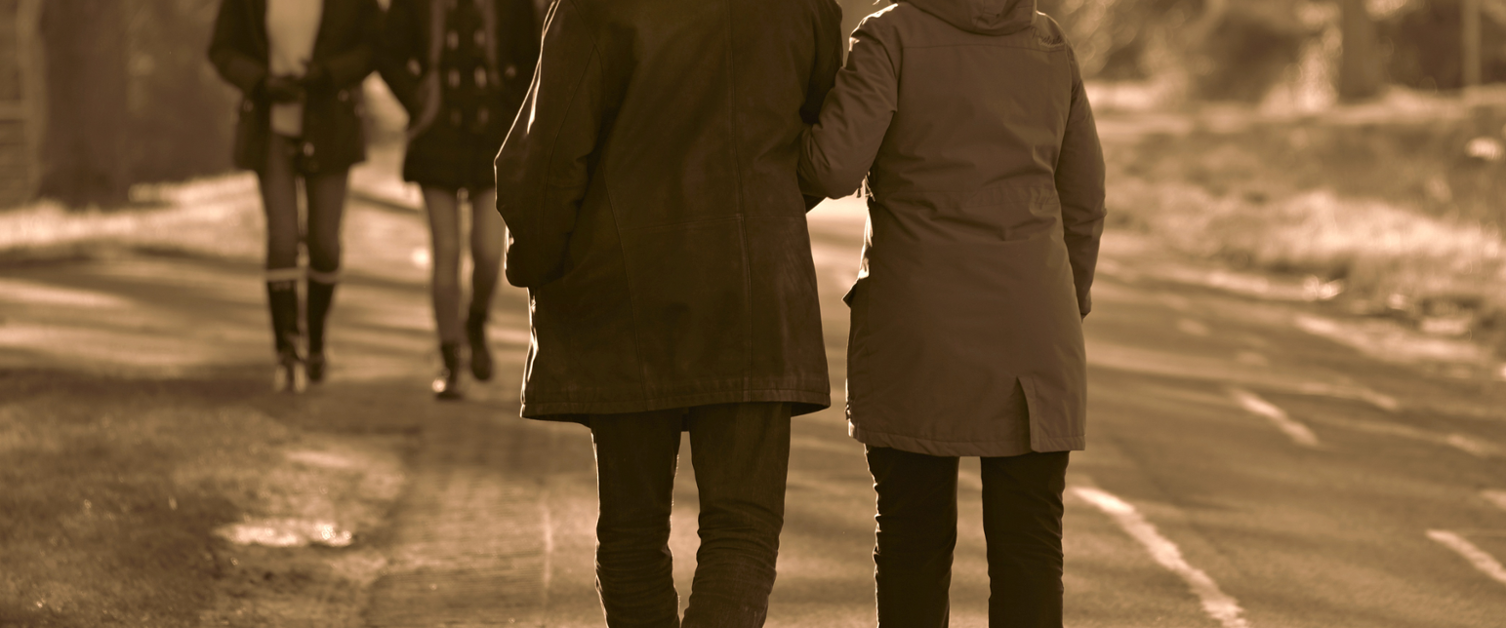 Sepia image of older couple out walking, arm in arm.