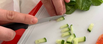 Person using knife to cut cucumbers in to small pieces