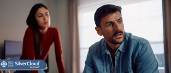 Image of looking away with worried expression on his face. Image of woman in background slightly blurred.
