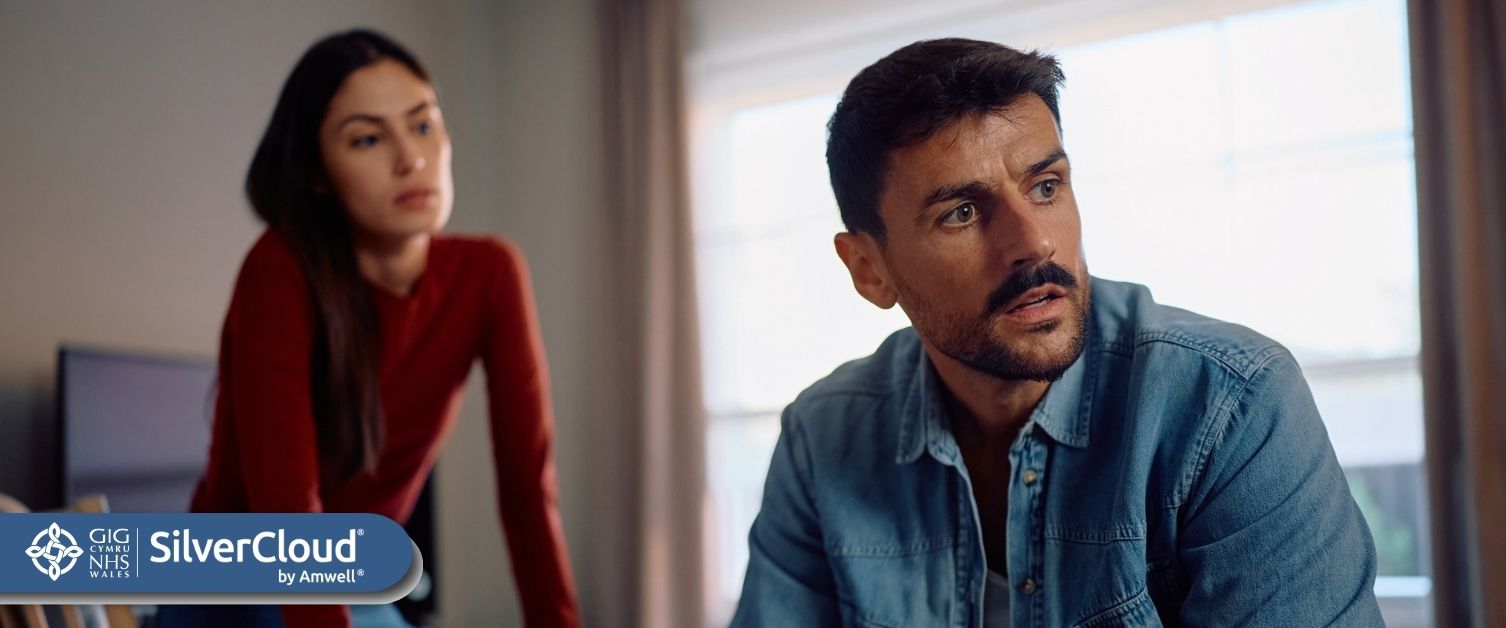 Image of looking away with worried expression on his face. Image of woman in background slightly blurred.