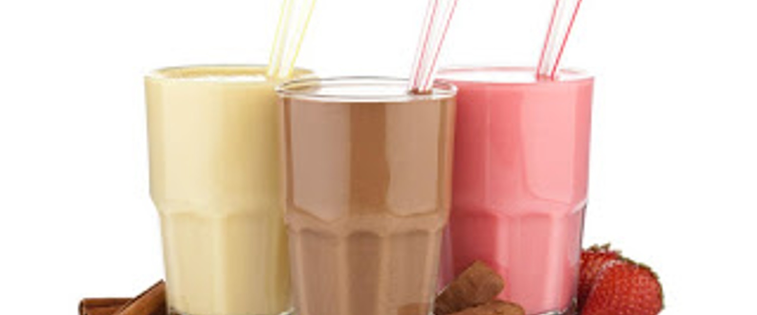 Vanilla, chocolate and strawberry milkshake in glasses with straws and two chocolate bars.