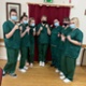 7 female apprentices wearing masks and green scrubs with their thumbs up