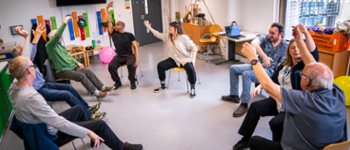 A room of patients sat in a chair circle, stretching their arms