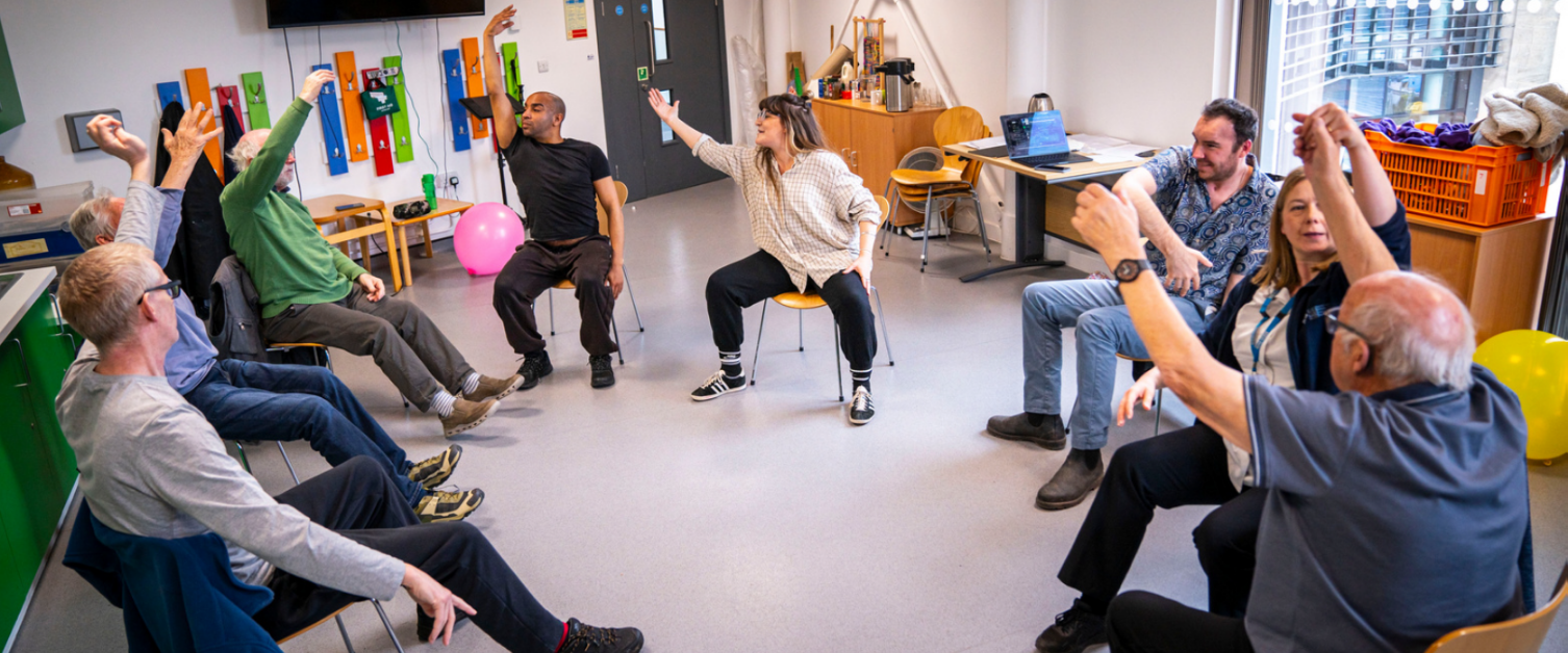 A room of patients sat in a chair circle, stretching their arms