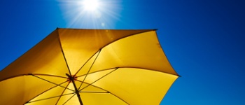 Yellow umbrella with bright sun and blue sky