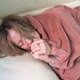 Woman lying on a sofa and going cold through the winter,blowing her hands to warm herself.