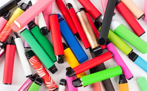 Set of colourful disposable electronic cigarettes of different shapes on a white background.