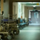 Copilot said:  English Alt Text  Hospital corridor with patient trolleys and seating lined along the hallway, leading towards double doors in the distance.