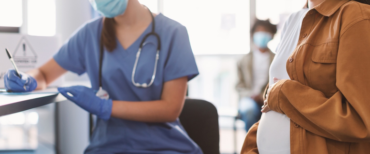 Pregnant woman in face mask visit midwife at hospital or medical clinic for consultation, midwife filling health record, selective focus on belly. Mother healthcare check up