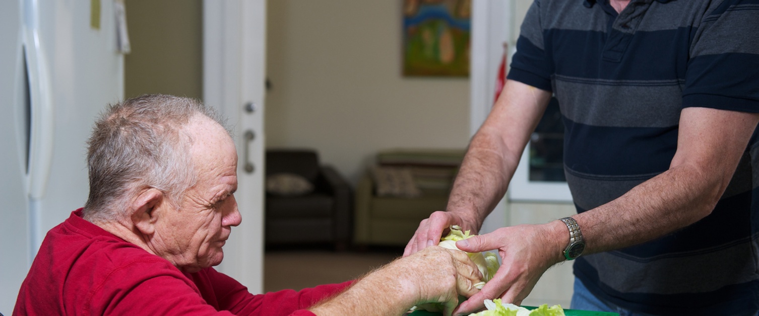 a carer  supporting a gentleman with a disability in making a meal.