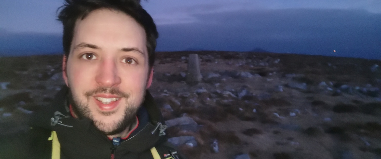 Ramblers Cymru Engagement and Communications Manager Brân Devey at the top of a hill