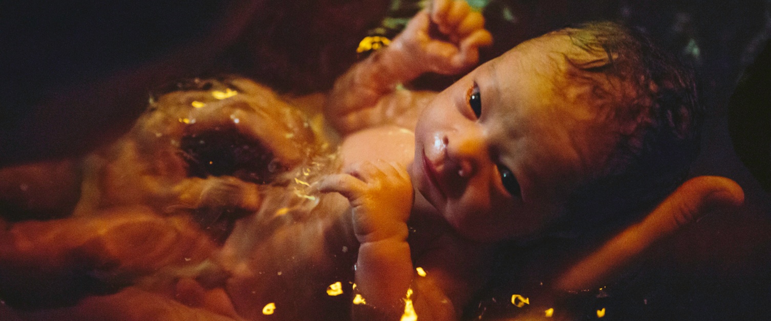 A newborn baby soaks in the water of the birthing pool