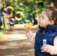 Pretty little girl blowing bubbles in the park