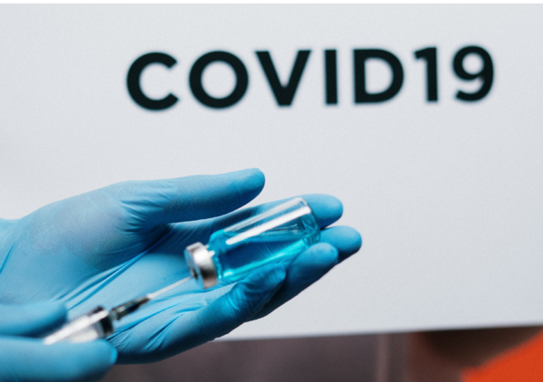 the image shows a hand wearing a protective glove holding what appears to be a vaccine in response to COVID. Note, these are stock images only and not based on real life vaccinations.