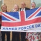A group of people are holding an Armed Forces Day flag.