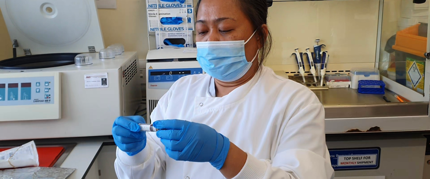 A staff member in the lab looks at a vial.