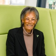 A woman is sat on a green chair and smiling.