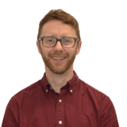 A man with glasses and a red shirt is smiling.