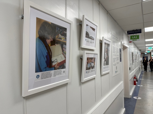 Exhibits from an art exhibition are framed on a white wall in a hospital corridor.