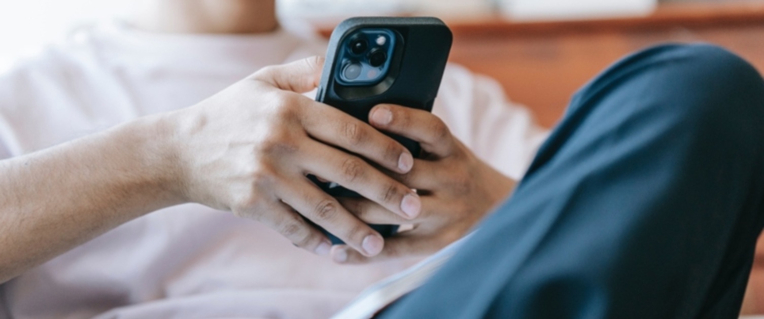 A person is sat on a sofa and using their phone.