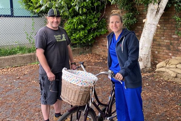 A member of staff at Velindre Cancer Centre is being handed her bike back by a bike technician.