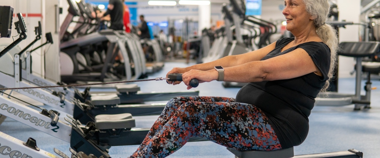 A woman is exercising on a rowing machine in a gym.