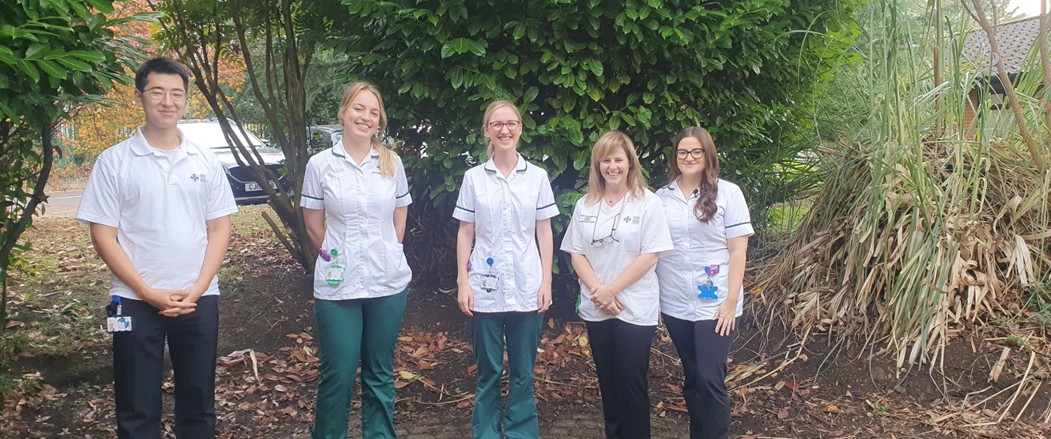 A group of staff are stood outside in a garden.