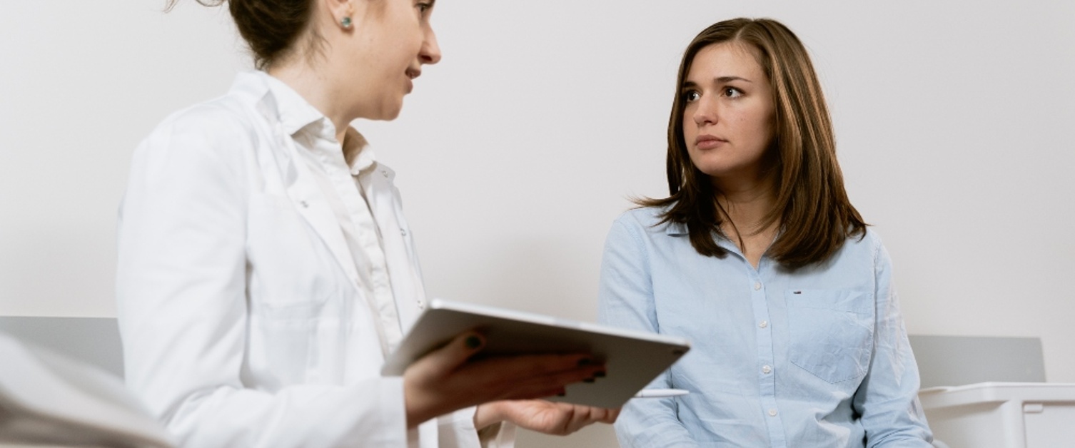 A clinician holds a tablet device and talks to a patient.