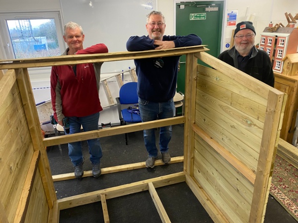 The team at Men Sheds stand next to the shed during its making.
