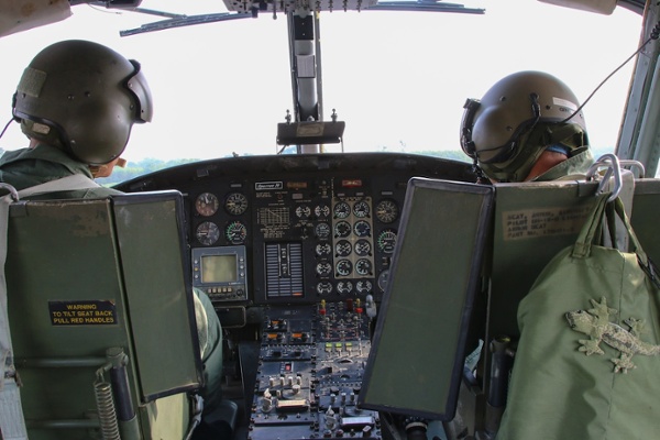 Two RAF service personnel are sat in a helicopter.