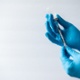 A pair of hands in gloves use a needle and medication.
