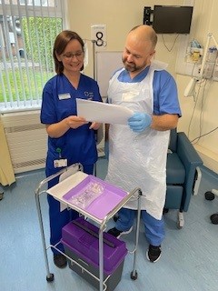 Fran Brown standing and looking at a document with new staff nurse David Longden