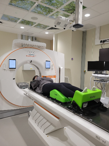 A person lying down next to a radiotherapy machine.