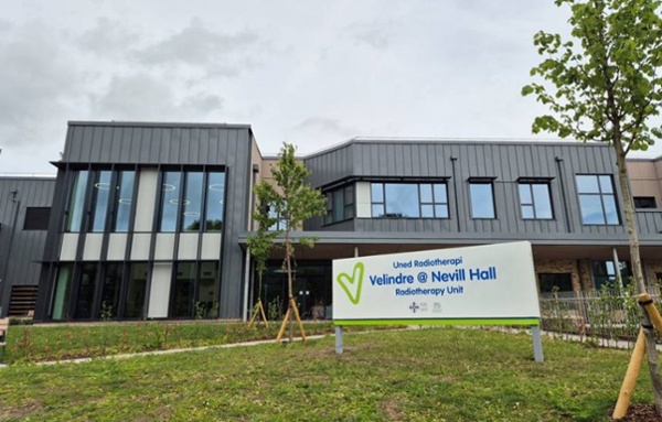 The exterior of modern hospital building with signage and grass in front.