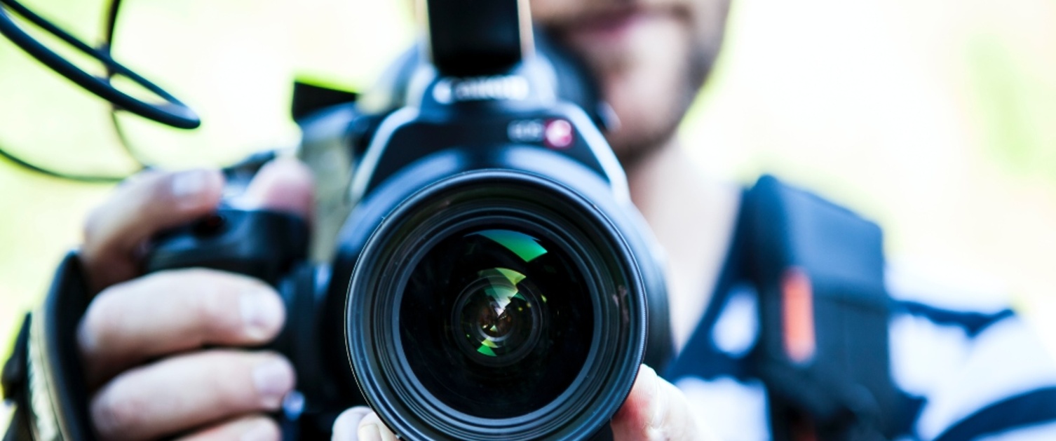 A camera lens is being held by a person and pointing forwards.