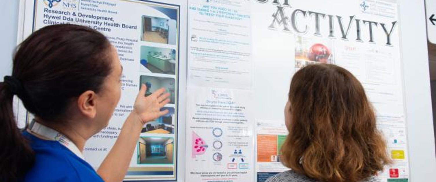 Two people look at a poster at a research event.