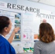 Two people look at a poster at a research event.