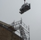 A crane lowering a machine into a building.