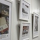 Images from the art exhibition are hung in white frames on a wall in a hospital corridor.