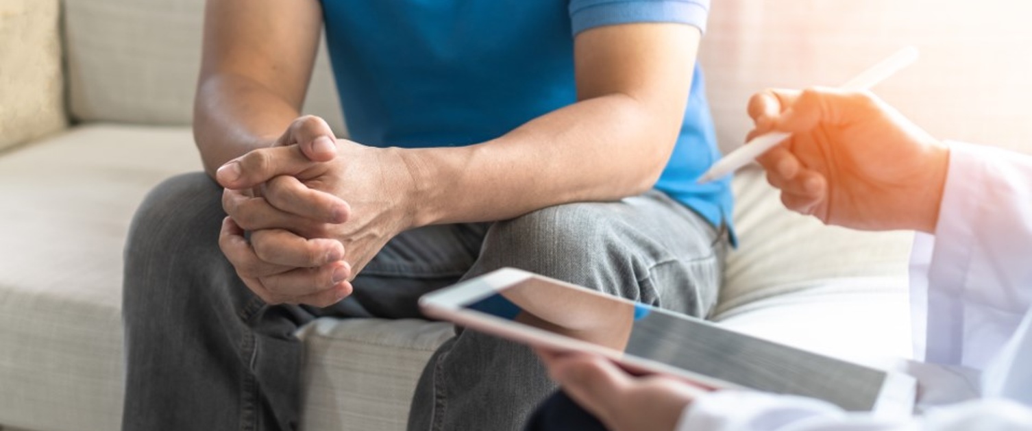 Two people are sat down, with one using a tablet device.