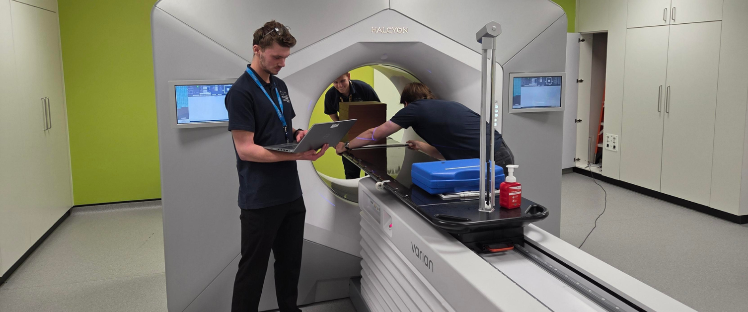 Radiographers standing around a treatment machine.