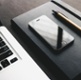 A stock image of a laptop, a mobile phone and a notepad and pen.