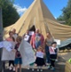 Thumbnail: A group of people stand outside a tent.