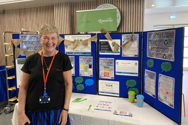 A member of staff at Velindre Cancer Centre is stood next to a display.